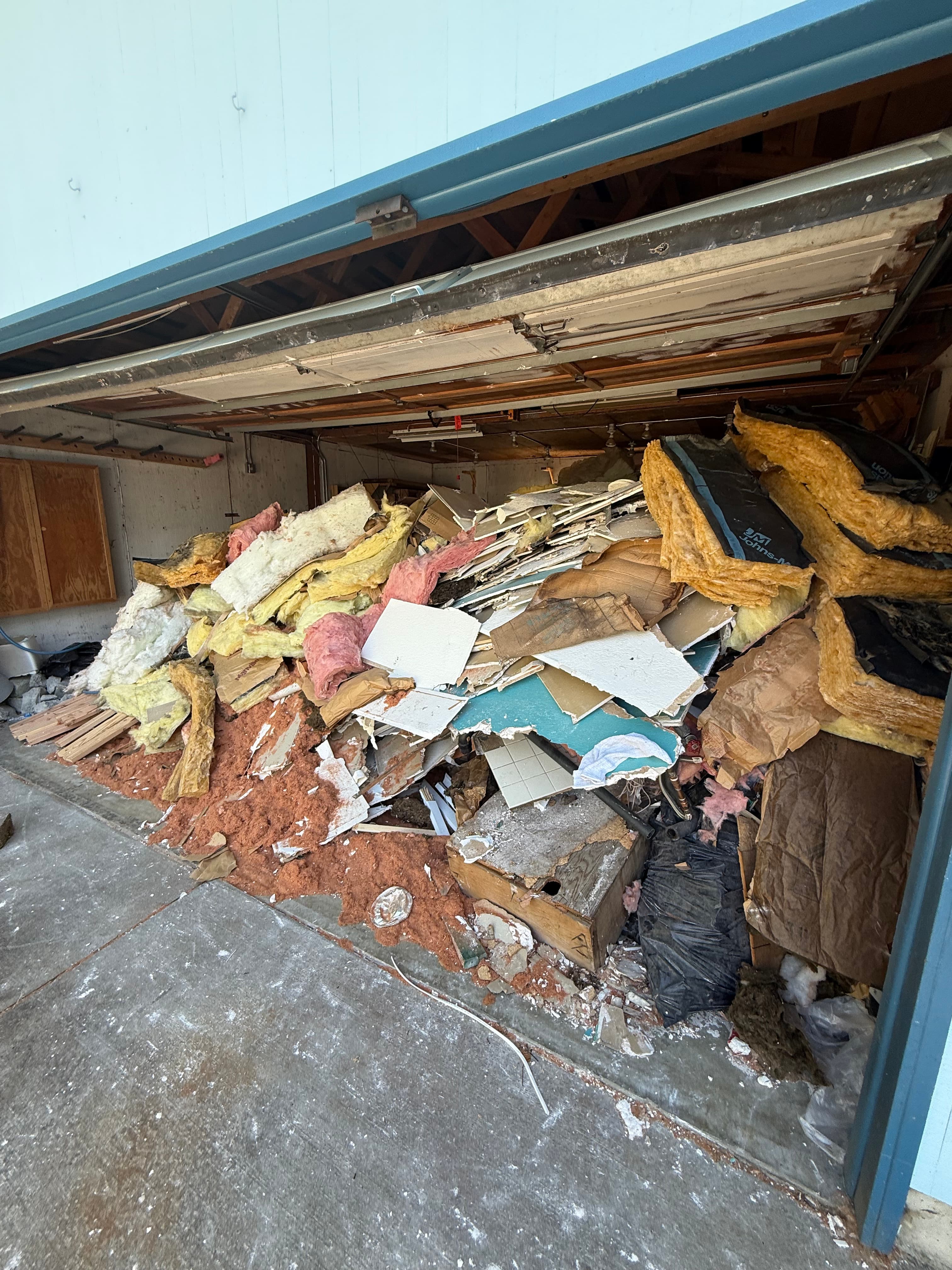 Garage filled with demo debris and insulation before junk removal